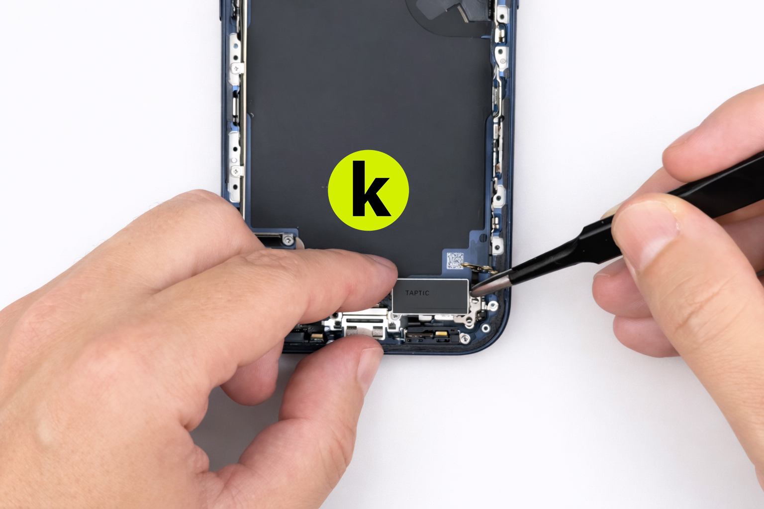 Инженер устанавливает нижний модуль Taptic в корпус телефона, фиксируя вибромотор перед завершением сборки.